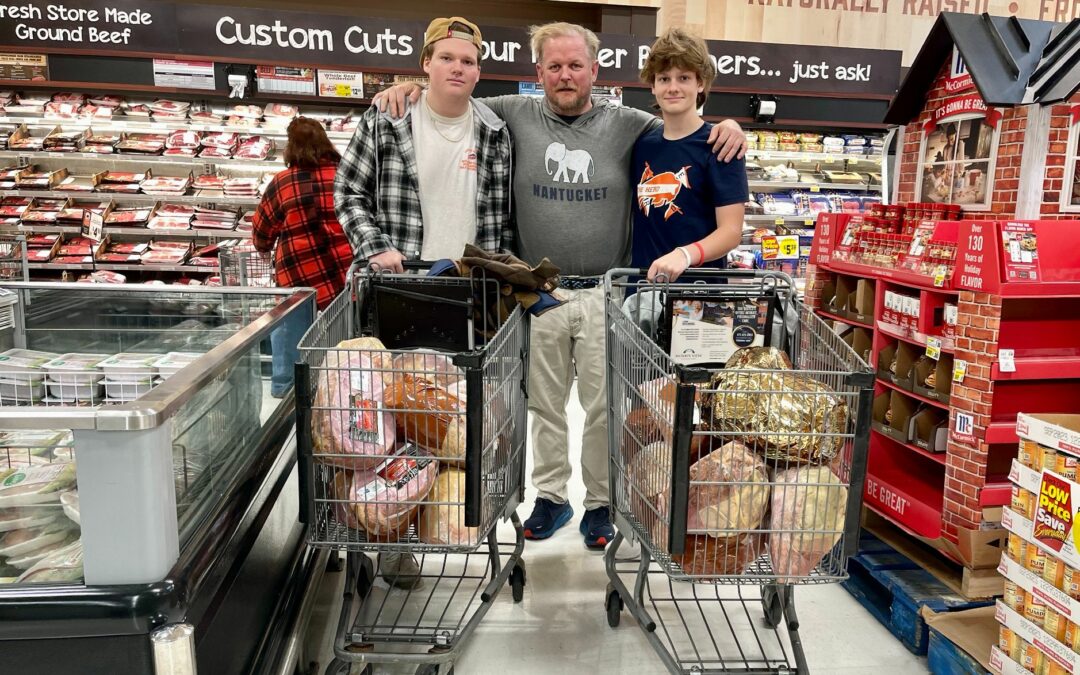 The Rodgers Foundation CEO Jamie Rodgers and sons at a grocery store with two carts full of holiday hams.