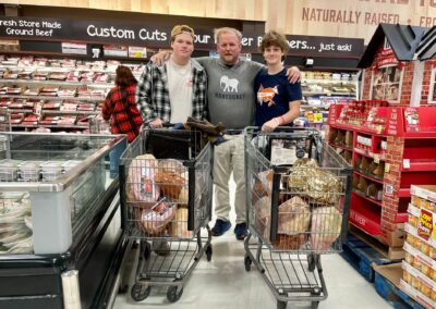 The Rodgers Foundation CEO Jamie Rodgers and sons at a grocery store with two carts full of holiday hams.